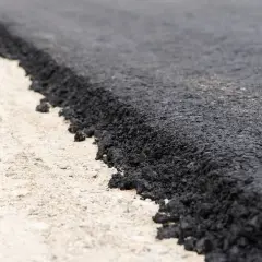 Zbliżenie na świeżo położony asfalt na jasnym podłożu.