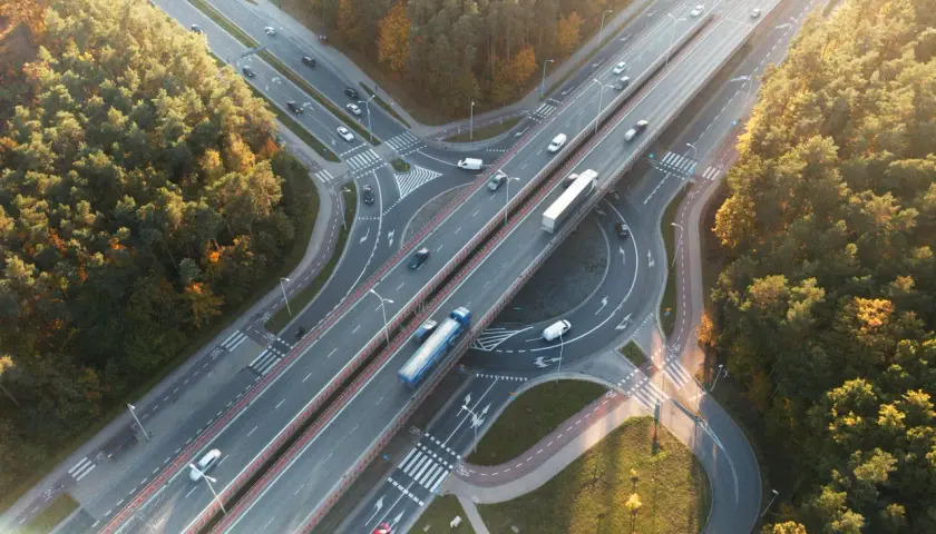 Widok z lotu ptaka na węzeł autostradowy otoczony lasem jesienią.