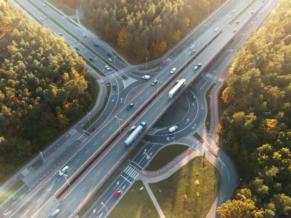 Widok z lotu ptaka na węzeł autostradowy otoczony lasem jesienią.